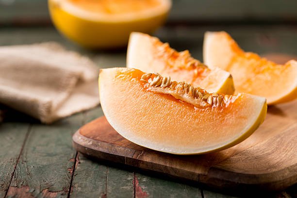 sliced ripe melon on a cutting board on rustic wooden background