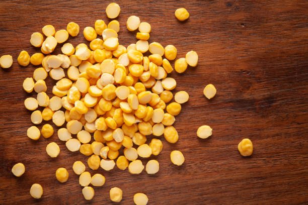 Macro Close-up of Organic Bengal Gram (Cicer arietinum) or split yellow chana dal cleaned on wooden top background.